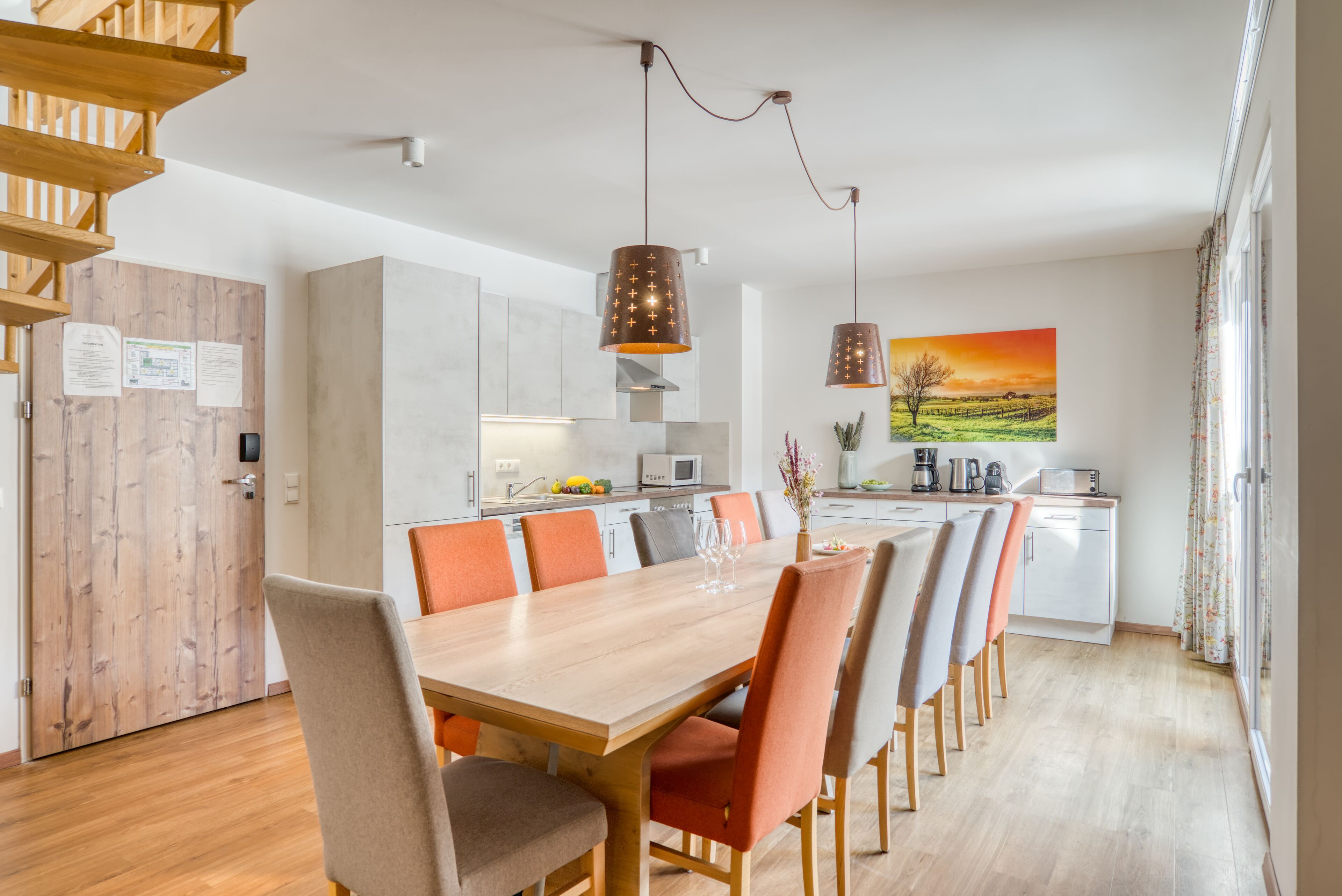 A modern kitchen with a wooden dining table and chairs, a built-in oven, and a microwave.