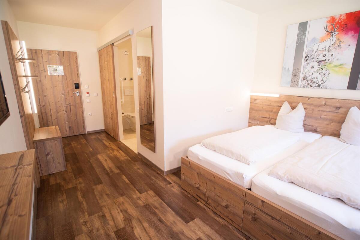 A bedroom with a wooden bed, a wooden wardrobe, and a sliding door closet.