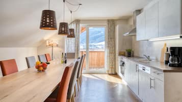 Una cocina moderna con una mesa de comedor de madera, sillas y lámparas colgantes.