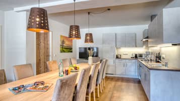 Una cocina moderna con una mesa de comedor de madera, sillas grises y luces colgantes.