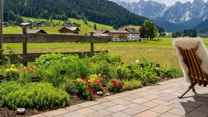 Un jardín con plantas identificadas, una cerca de madera y una silla.