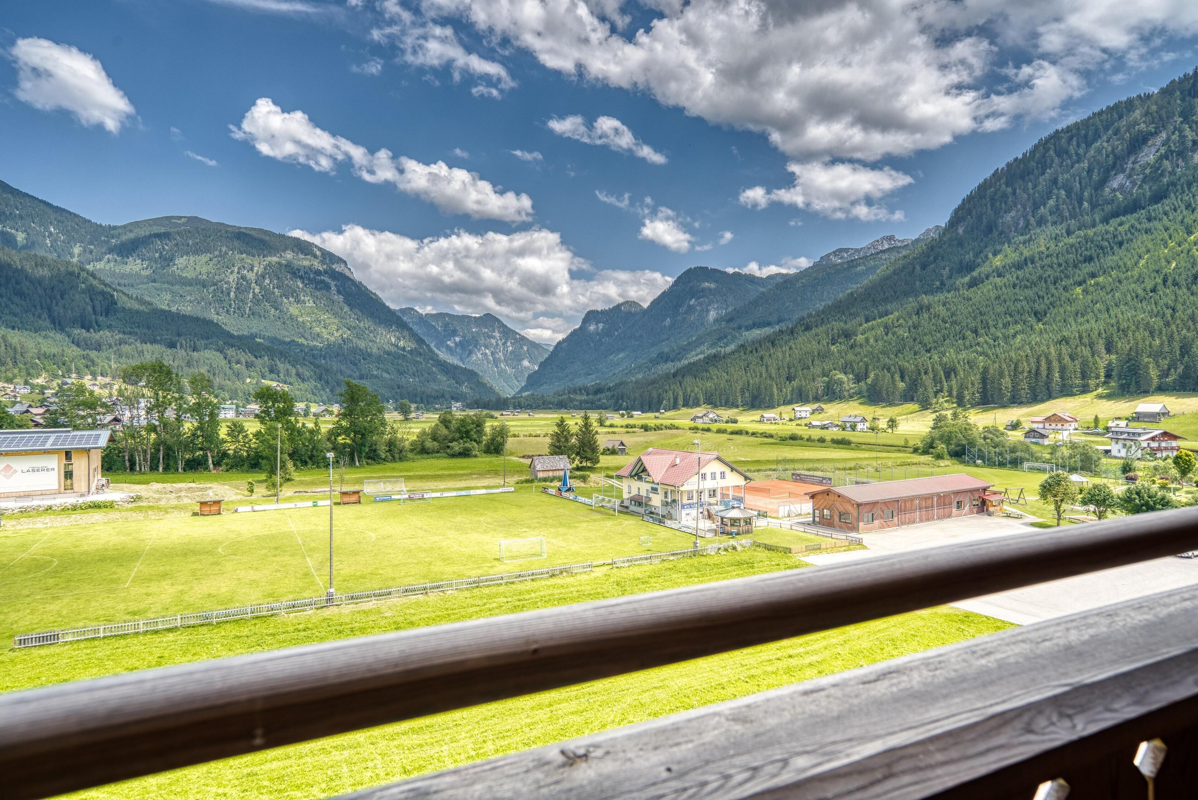 A mountain landscape with a village, houses, and a sports field.