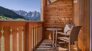 Ein Holzbalkon mit Blick auf Berge, einem Tisch und zwei Korbstühlen.