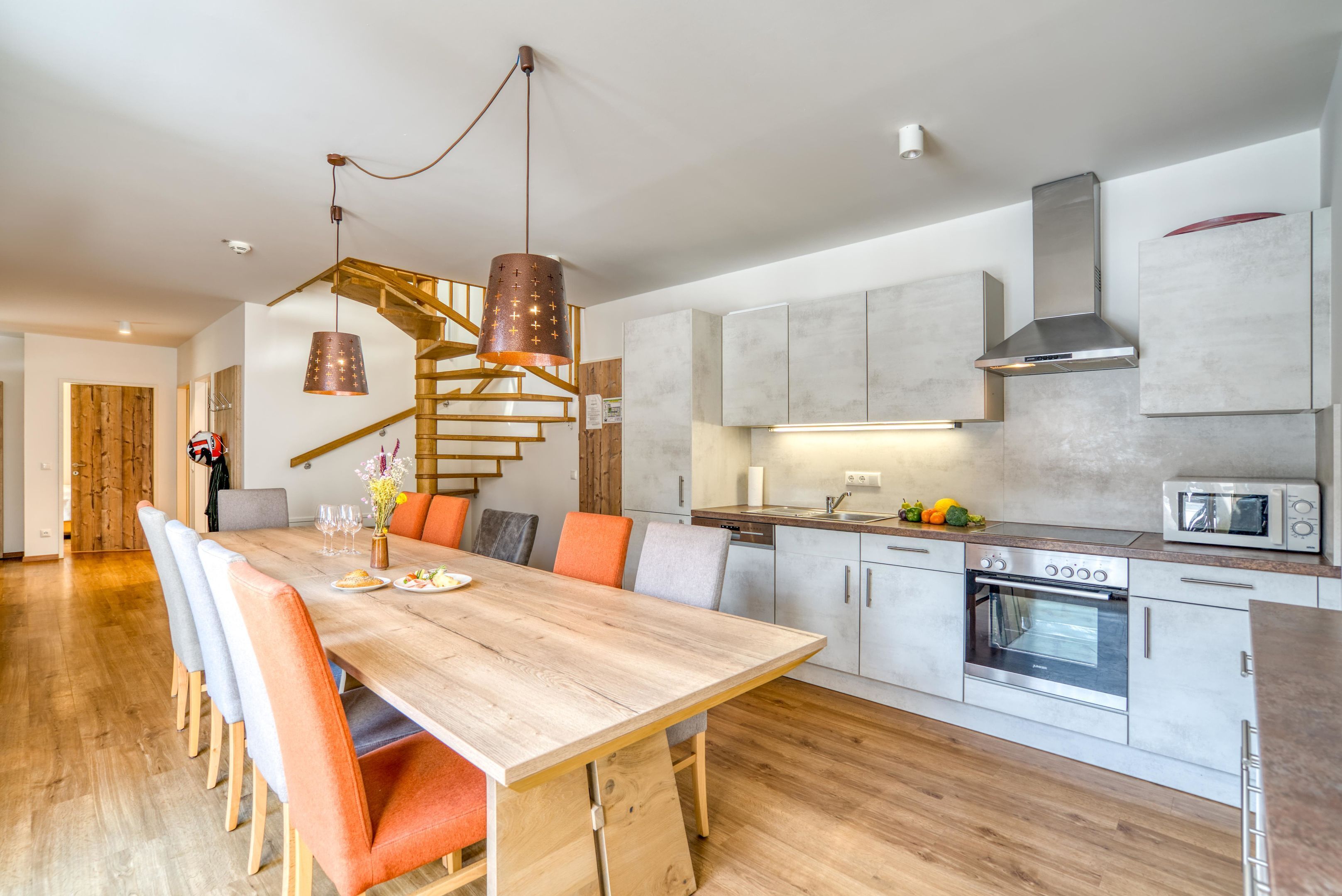Una cocina moderna con una mesa de comedor de madera, electrodomésticos integrados y una escalera.
