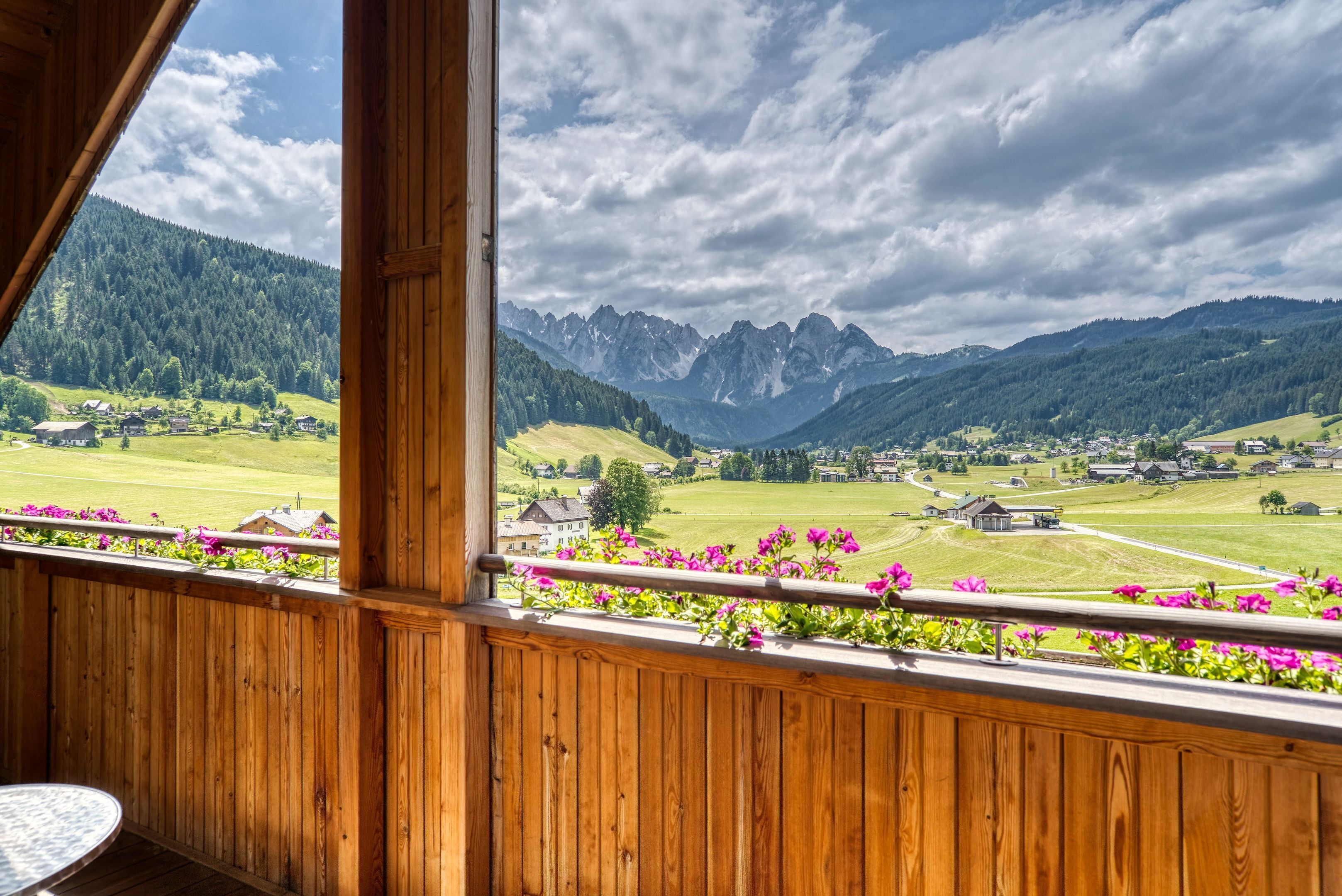 Ein Holzbalkon mit Blick auf eine Berglandschaft und ein Dorf darunter.