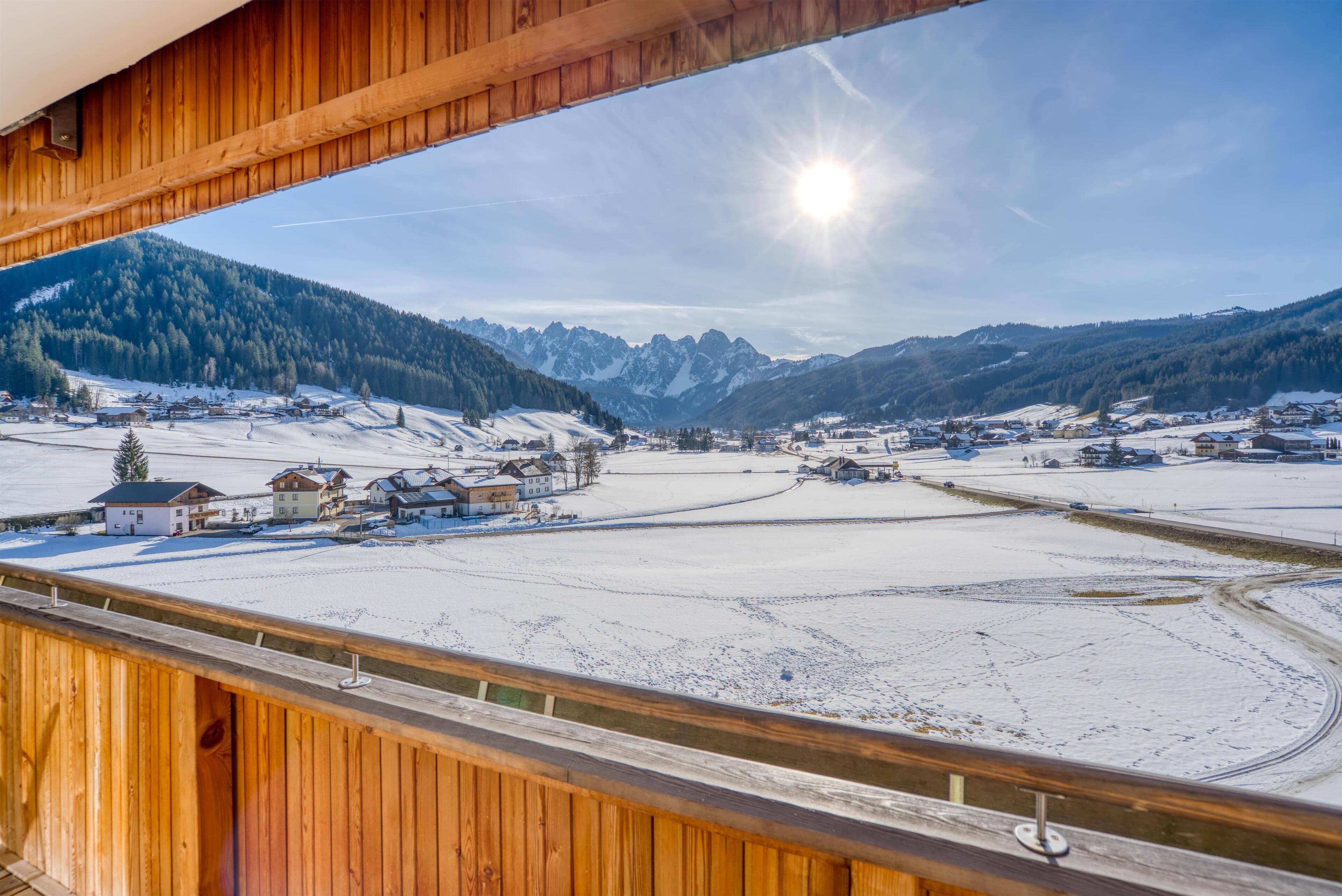 A snowy mountain landscape with a village and a wooden balcony.