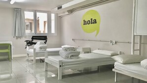 Quarto de hotel com duas camas, uma escrivaninha, uma cadeira e uma janela com cortinas.
