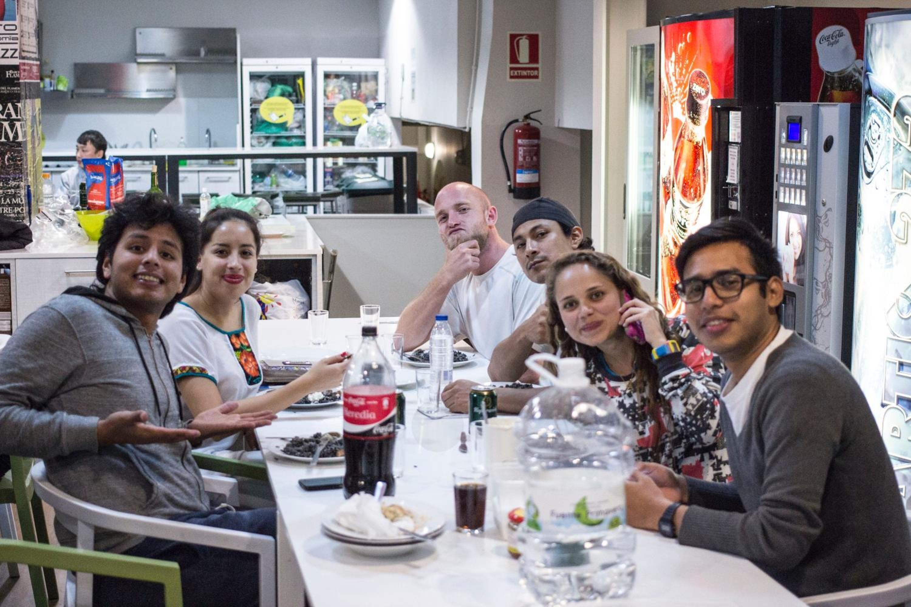 Un grupo de personas sentadas alrededor de una mesa en un restaurante, con una cocina al fondo.