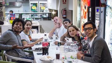 Un grupo de personas sentadas alrededor de una mesa en un restaurante, con una cocina al fondo.