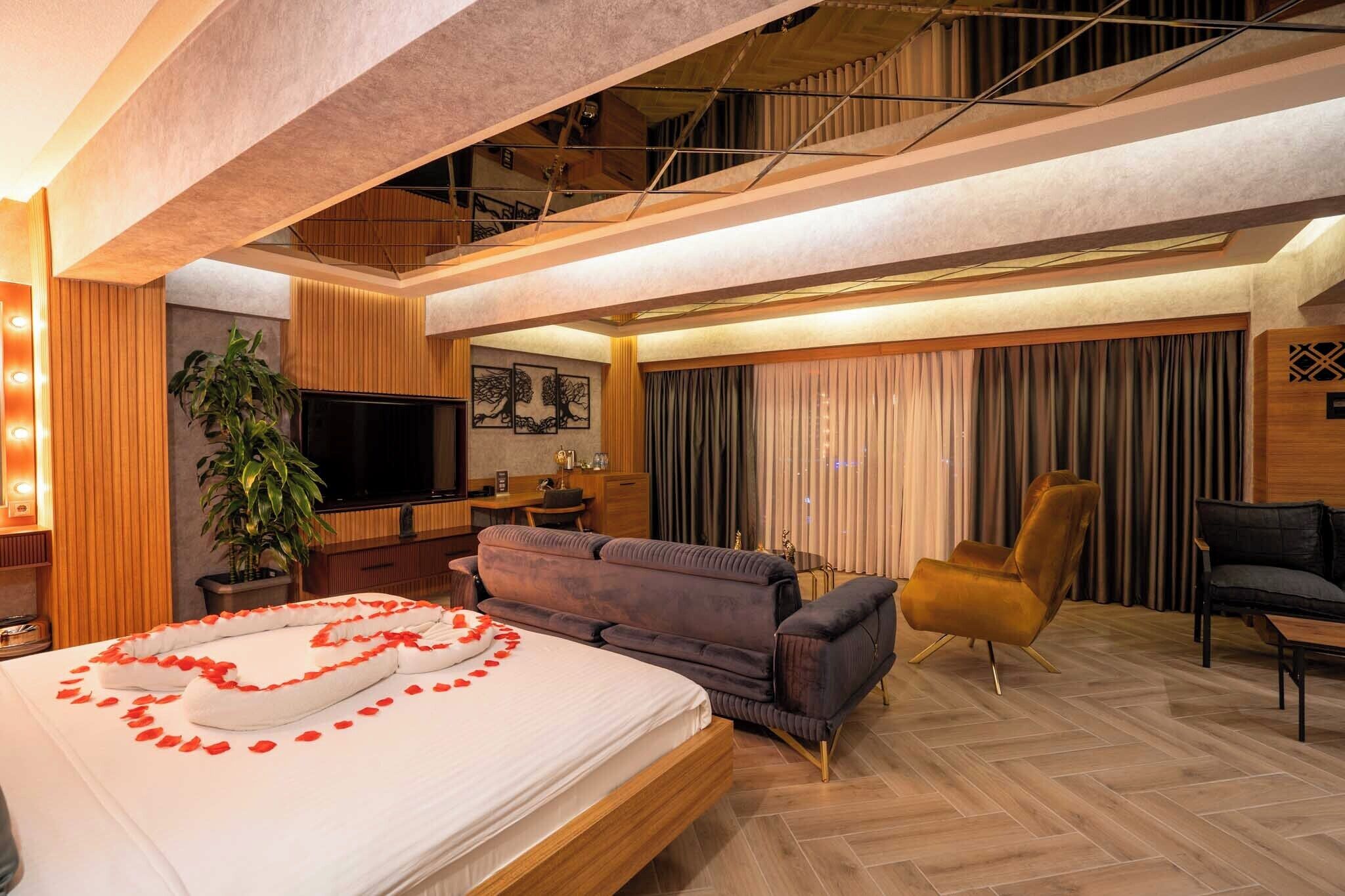 Een moderne hotelkamer met een bed, bank, fauteuil, televisie en een trap.