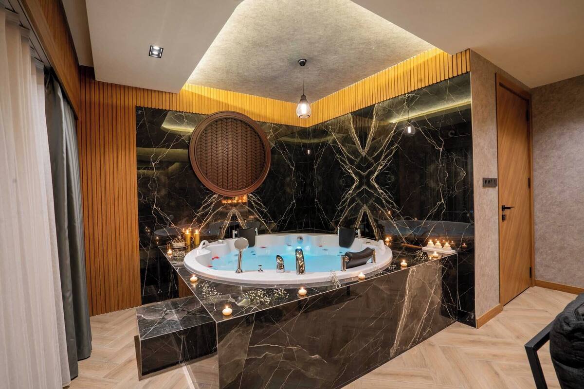 A modern bathroom with a marble vanity, a round mirror, and a freestanding bathtub.