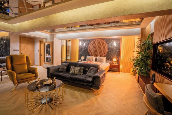 A modern hotel room with a bed, a sofa, a coffee table, and a TV. - Leman Hotel - Boutique Class (Denizli)