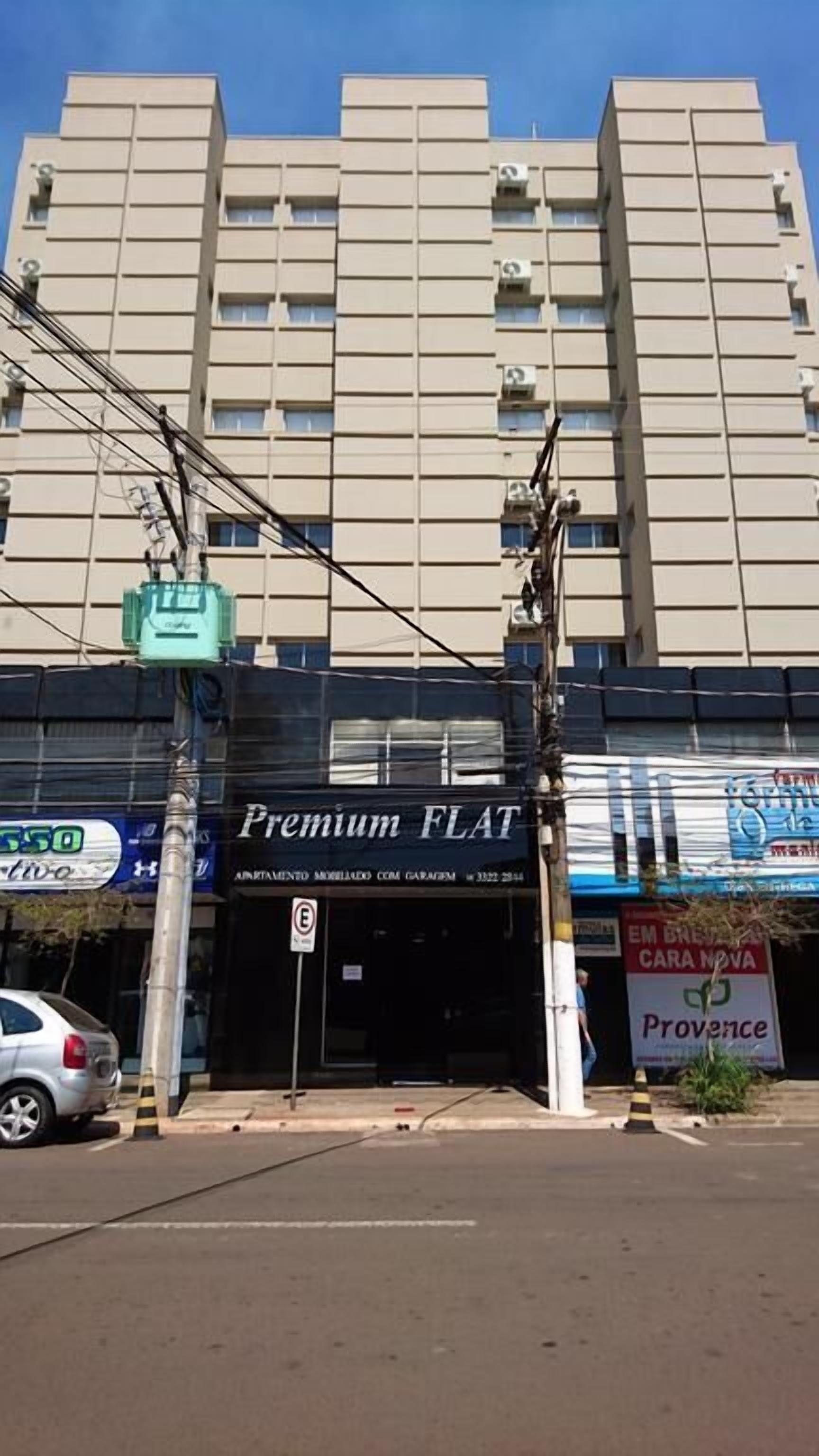 Un immeuble à plusieurs étages, une devanture de magasin portant l’inscription « Premium FLAT », et une enseigne indiquant « Provence ».