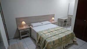 A hotel room with a bed, two bedside tables with lamps, a desk, and a chair.