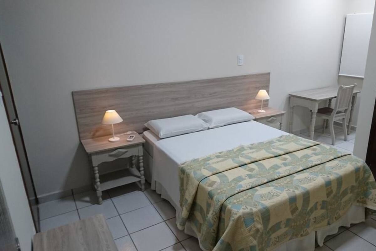 Une chambre d’hôtel comprenant un lit, deux tables de chevet avec des lampes, un bureau et une chaise.