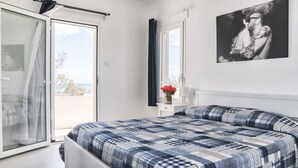 A bedroom with a bed, a nightstand, a window with curtains, and a wall-mounted picture. - Centro Vacanze Lido Smeraldo (Lecce)