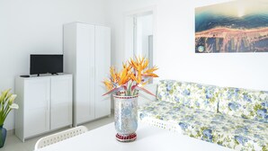 A modern living room with a white sofa, a white cabinet, and a television on top. - Centro Vacanze Lido Smeraldo (Lecce)
