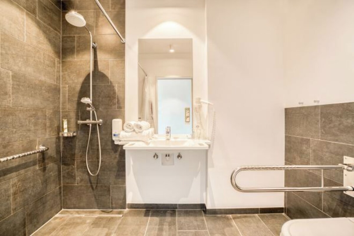A modern bathroom with a shower, a sink with a mirror, and a toilet.