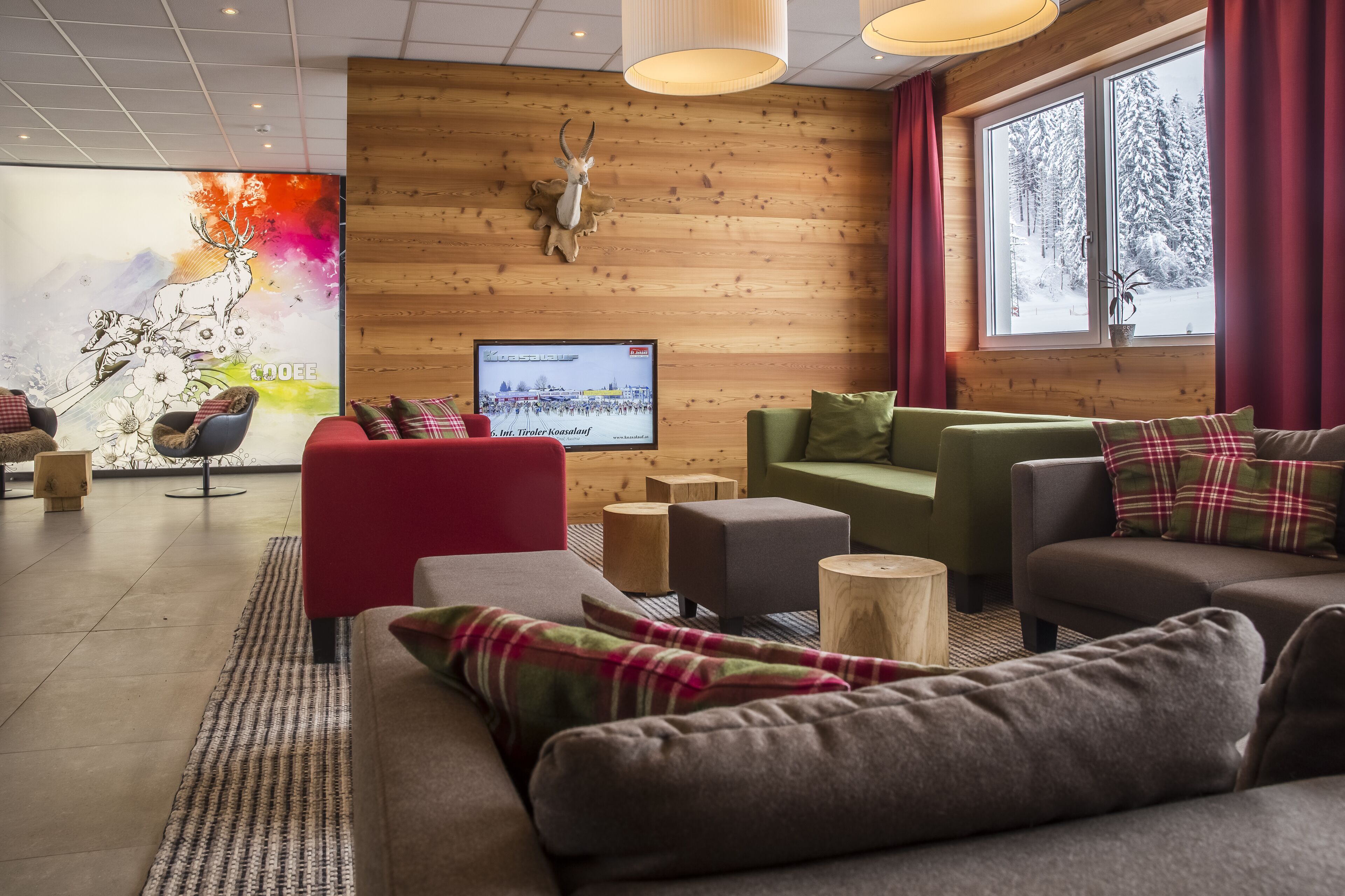 Un salón moderno con una pared de madera, una cabeza de venado montada y un ventanal con vistas a un paisaje nevado.