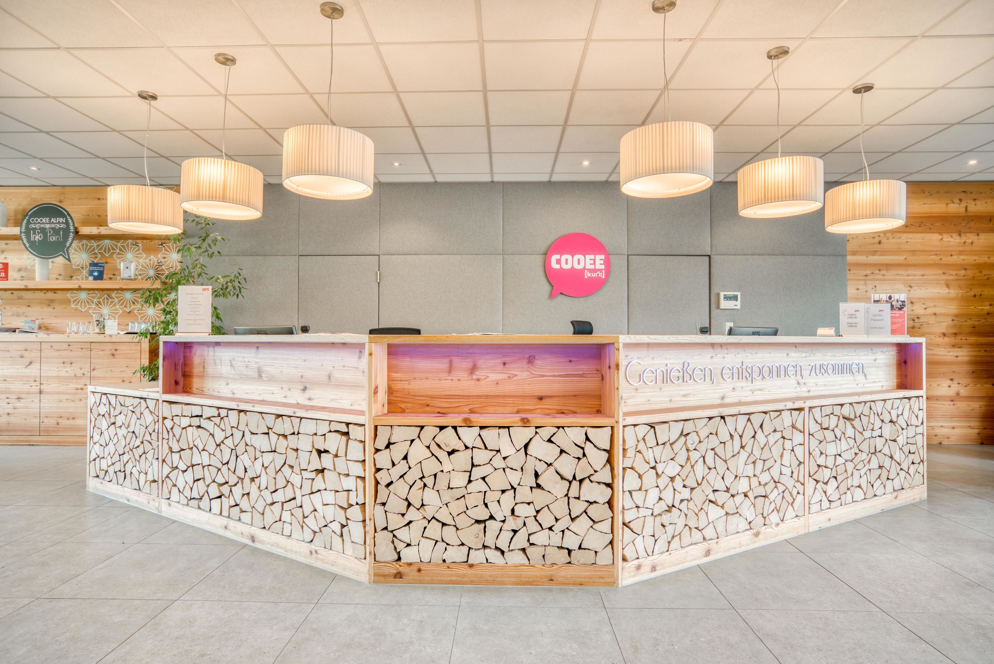 Un comptoir d’accueil au design en bois, une enseigne « COOEE » et un panneau affichant le menu.