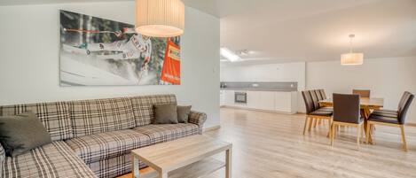 A modern living room with a sofa, a coffee table, and a dining area with chairs and a table.