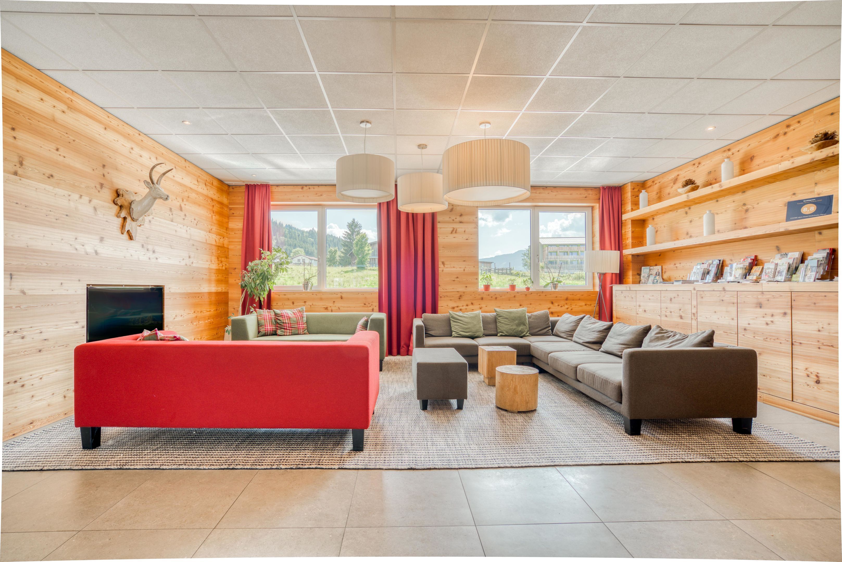Una sala de estar moderna con un sofá rojo, un sofá marrón y un televisor en la pared izquierda.