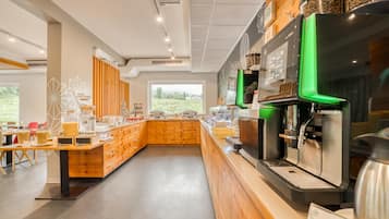 Una cafetería moderna con mostrador de madera, máquinas de café y vistas al exterior.