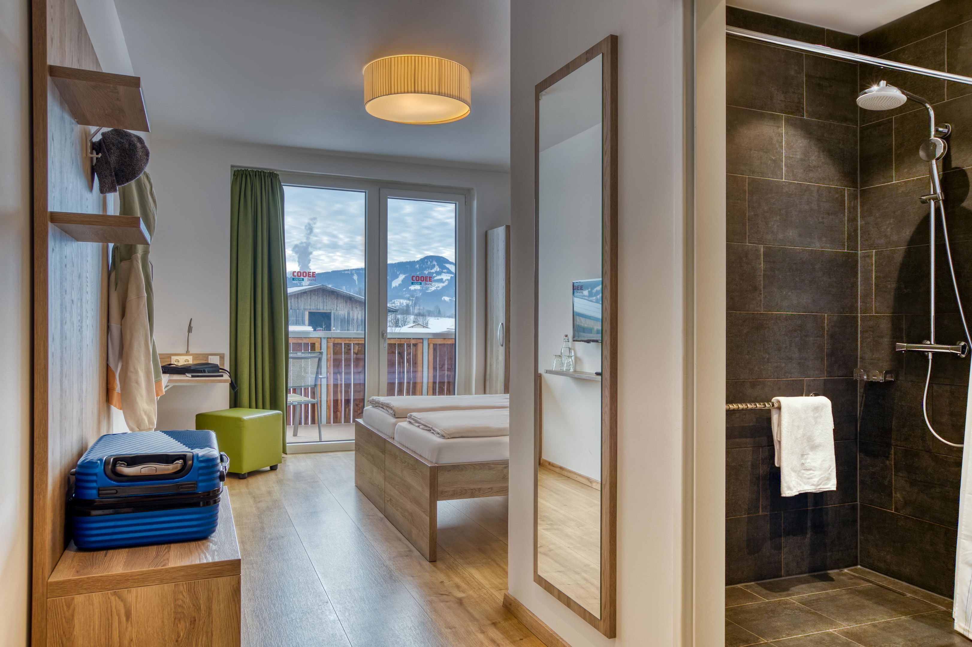 A modern bathroom with a shower, a bench, and a suitcase on the floor.