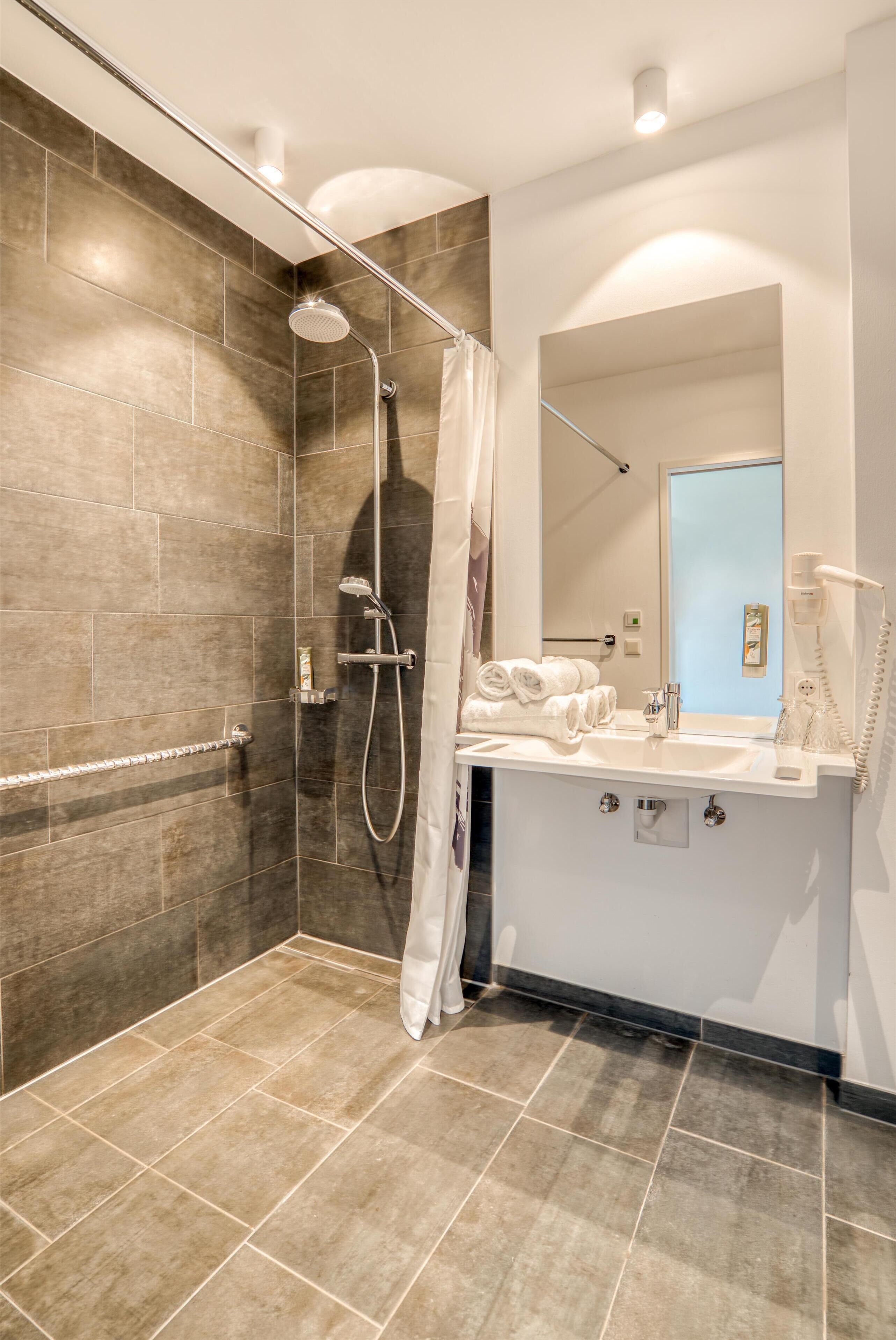 A modern bathroom with a glass-enclosed shower, a white sink, and a mirror above it.
