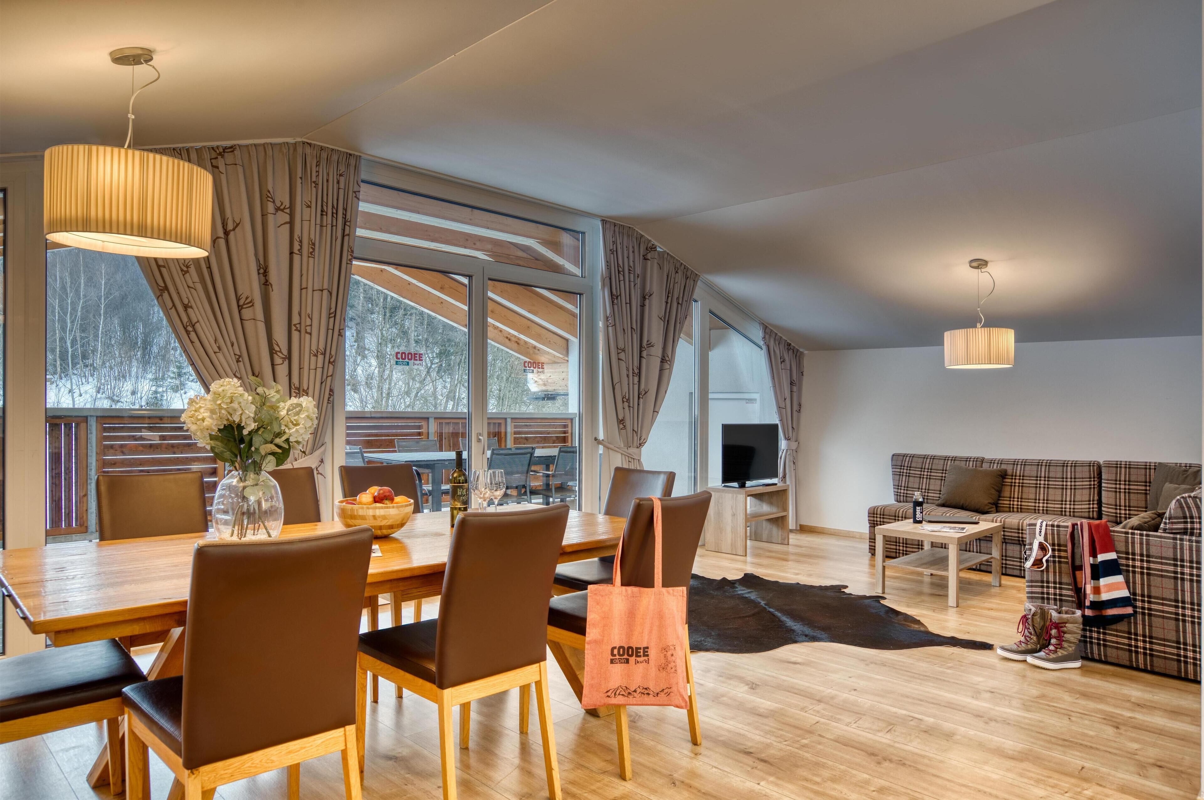 A modern living room with a dining area, large windows, and a sofa.
