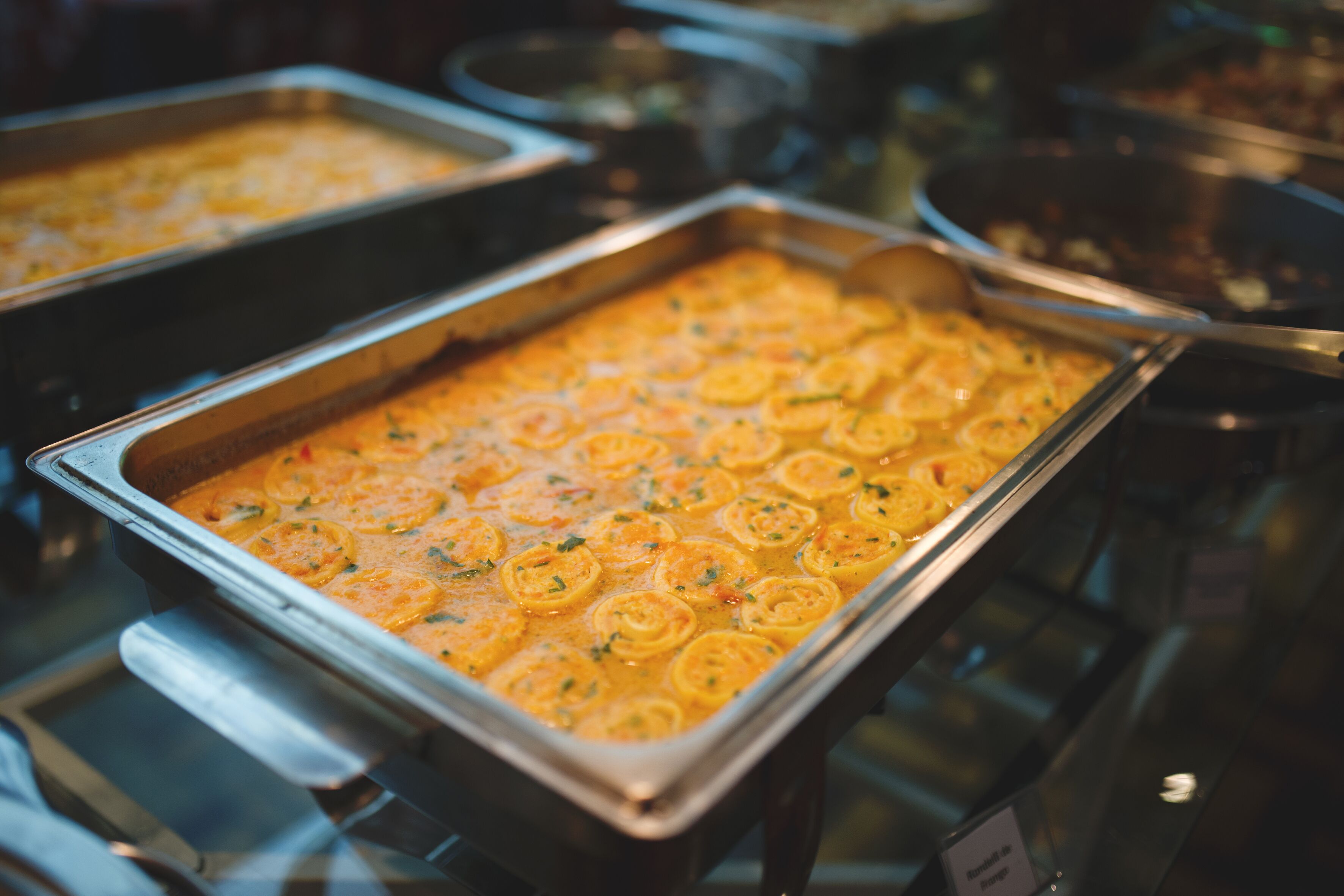 Un buffet proposant une variété de plats, dont un plat crémeux à l’orange, présenté sous forme de cercles, et une pancarte indiquant « Buffet du jour ».