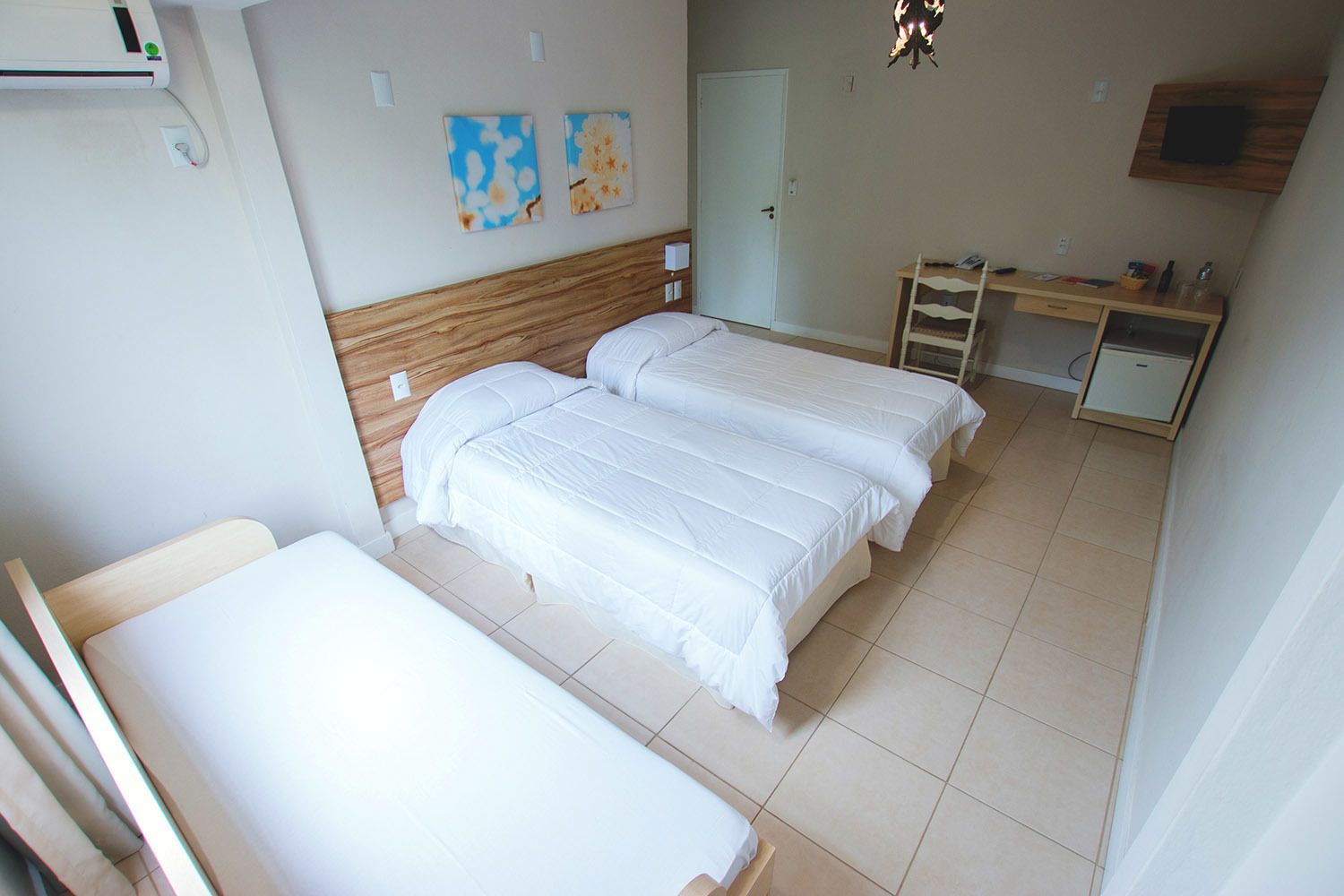 Een kamer met twee bedden, een bureau, een stoel en een deur.