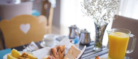 A breakfast table with croissants, pastries, fruit, and a pitcher of orange juice.