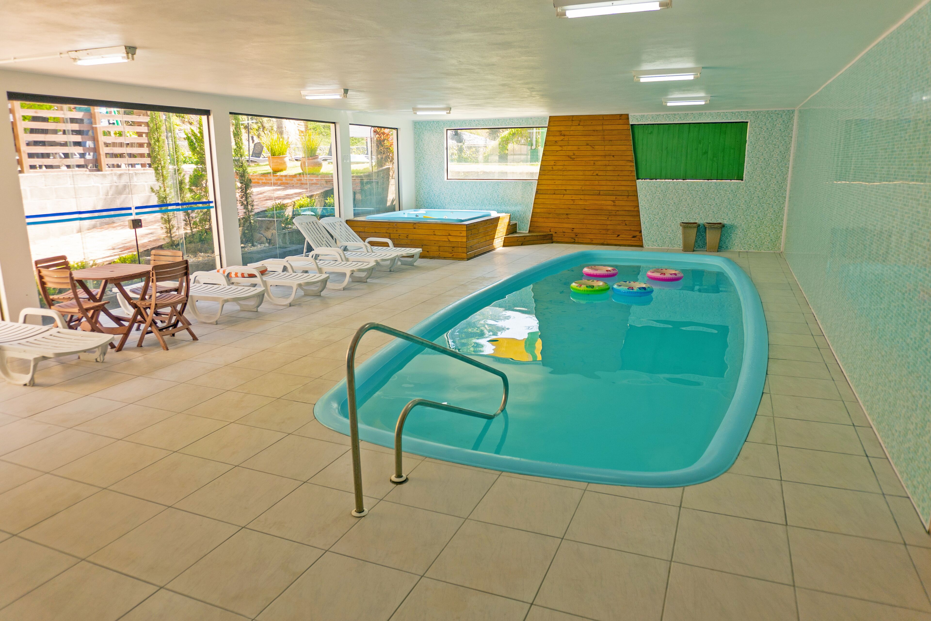 Ein Innenpool mit Holzterrasse, Liegestühlen und einem Whirlpool.