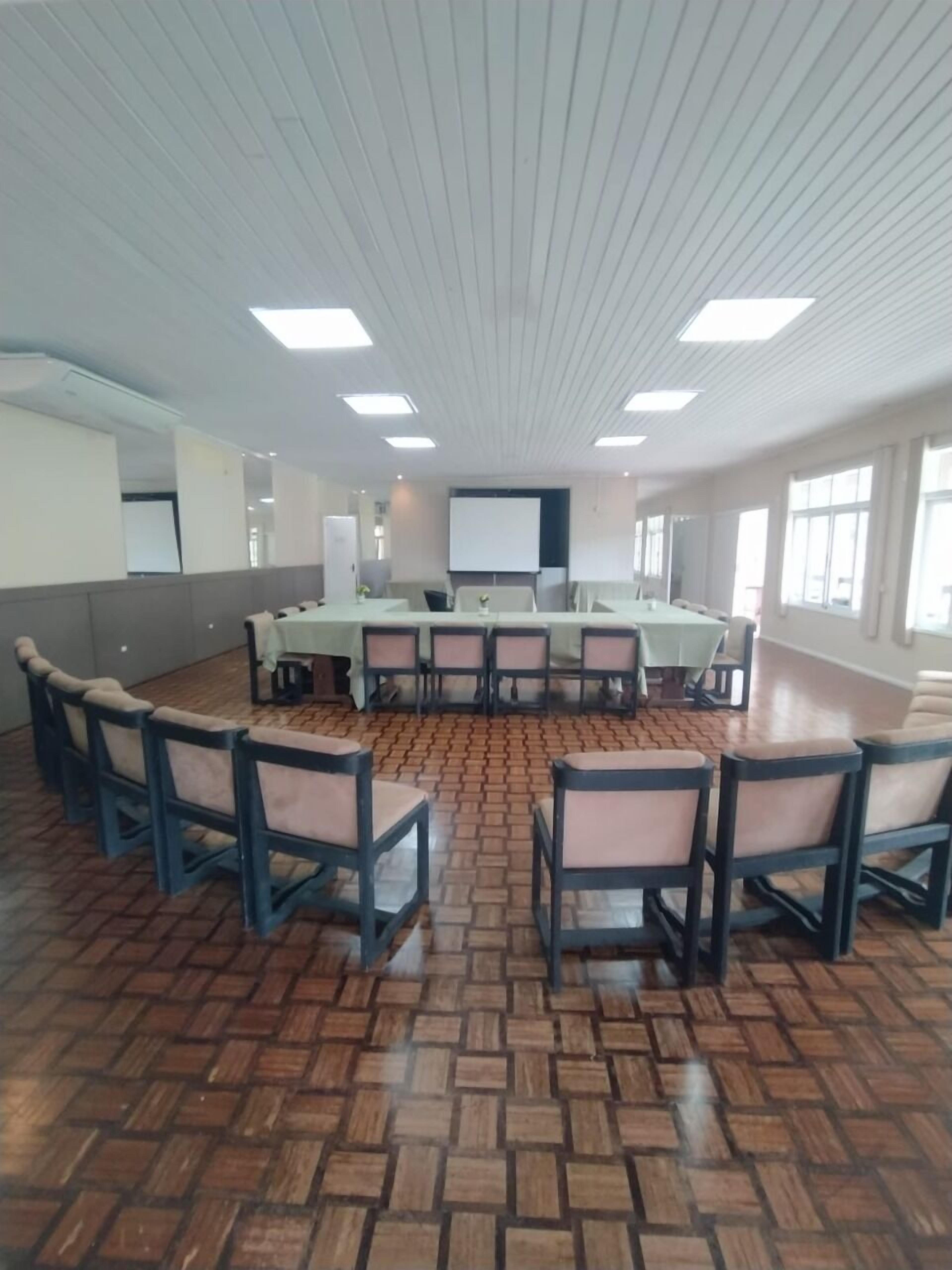 Une salle de conférence équipée d’une longue table, de chaises et d’un écran de projection.