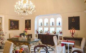A formal dining room with a chandelier, a Christmas tree, and a collection of framed artworks. - Relais La Rupe (Sorrento)