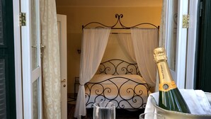 A room with a bed, a bottle of champagne, two glasses, and a tray with nuts. - Relais La Rupe (Sorrento)