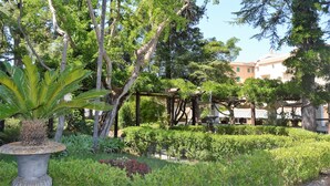 A garden with various plants, a pergola, and a building in the background. - Relais La Rupe (Sorrento)