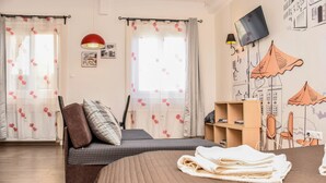 A bedroom with a bed, a sofa, a TV, and a wall with a cityscape mural. - Diamond Astoria (Budapest)