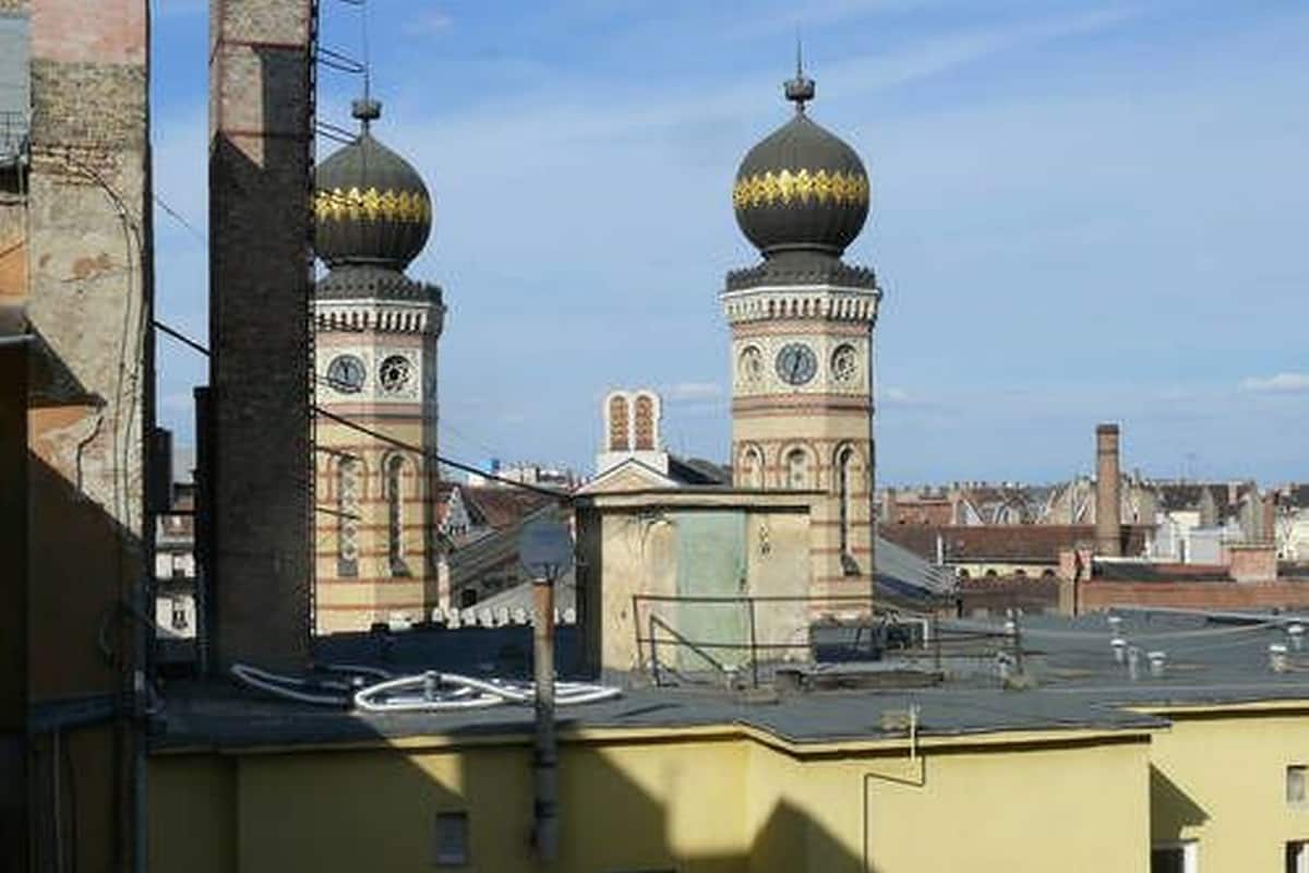A building with two prominent towers featuring clock faces and domed tops.