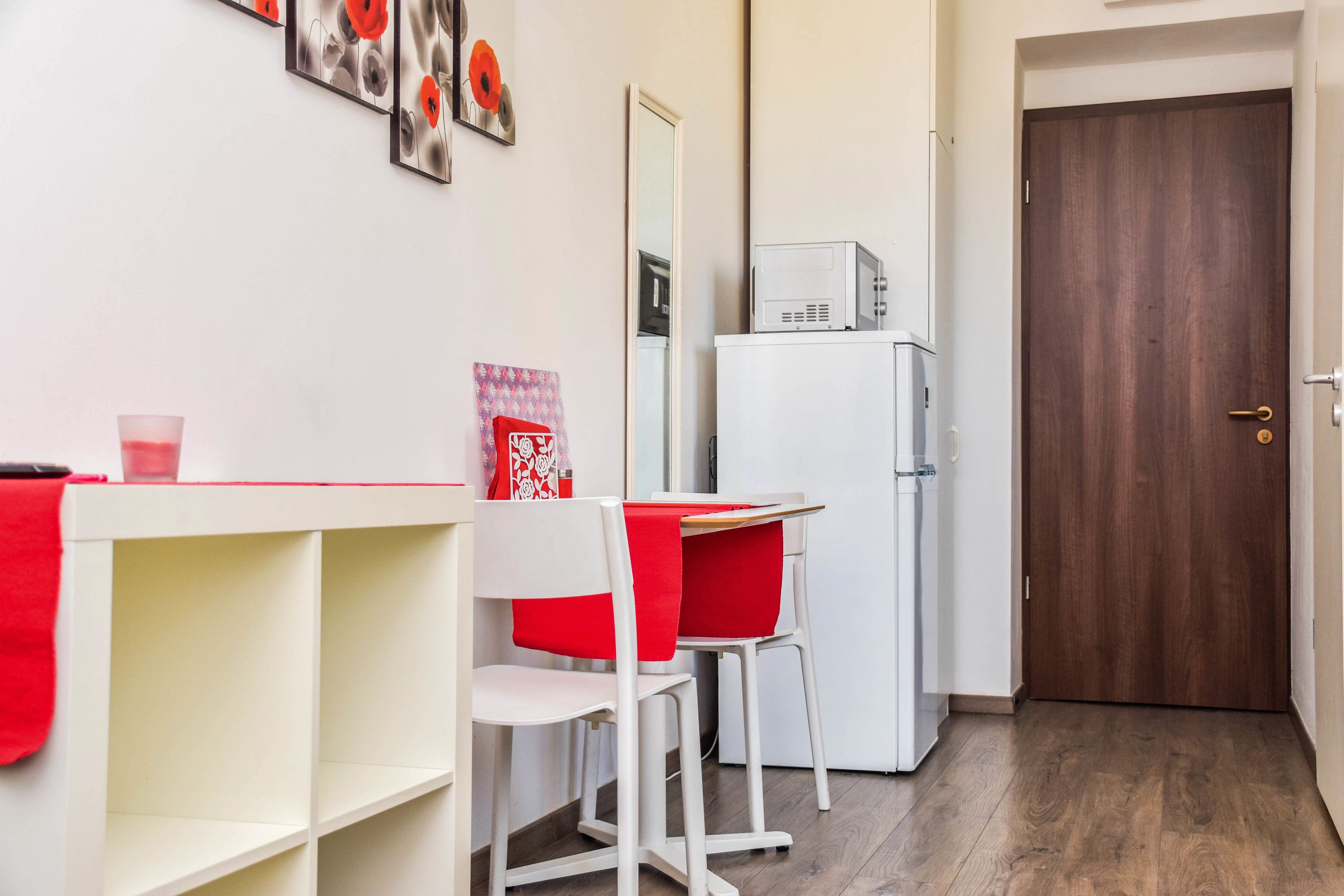 A compact kitchen with a white refrigerator, a microwave, and a wooden door.