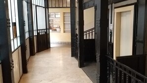 A corridor with a tiled floor, black metal railings, and a door with a light switch. - Diamond Astoria (Budapest)