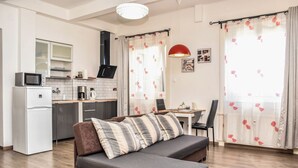 A modern living room with a sofa, a dining area, and a kitchen. - Diamond Astoria (Budapest)