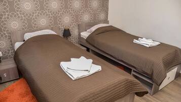 Een hotelkamer met twee enkele bedden, elk met een bruine sprei en witte handdoeken.