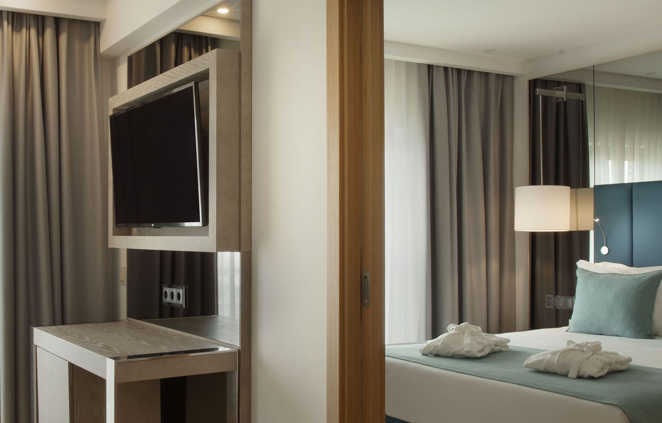Ein Hotelzimmer mit Bett, Nachttisch, Fernseher und Spiegel.