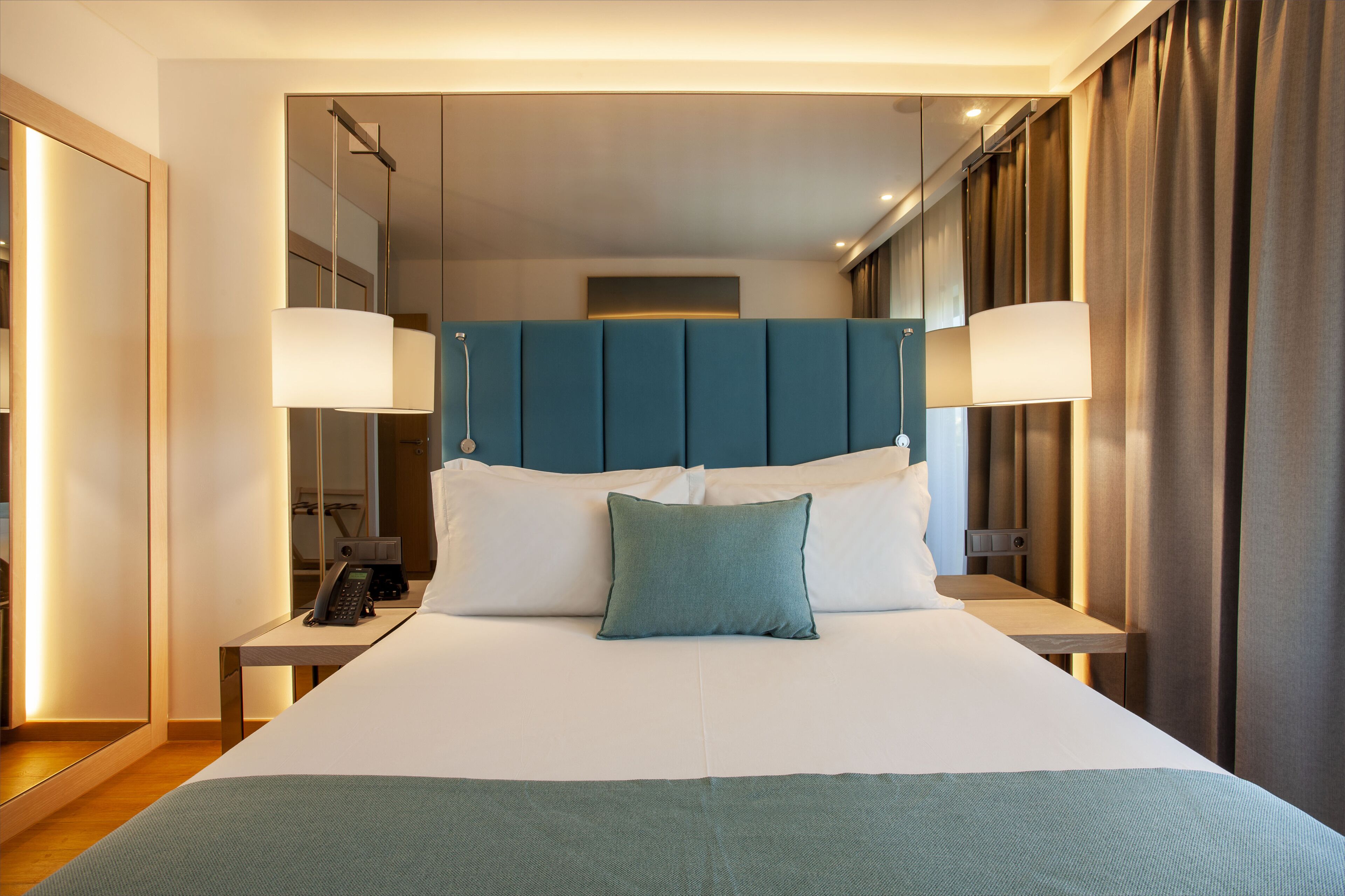 Une chambre d’hôtel moderne avec un grand lit, un téléphone sur la table de chevet et une lampe de chevet.
