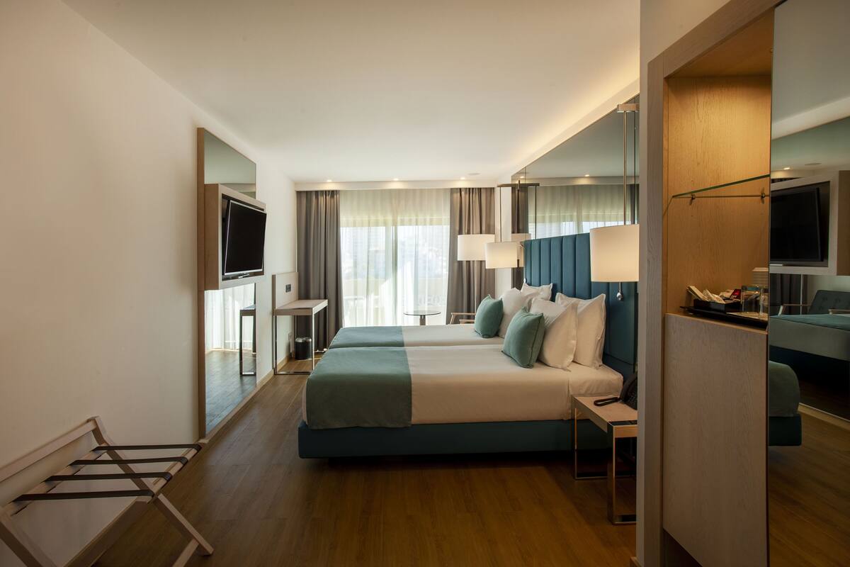 A hotel room with a bed, a desk, a TV, and a view of the outdoors.