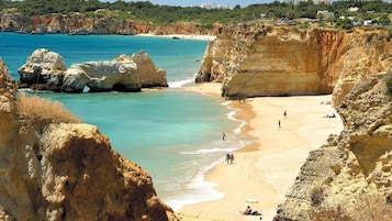 Una playa costera con acantilados rocosos y agua turquesa cristalina.