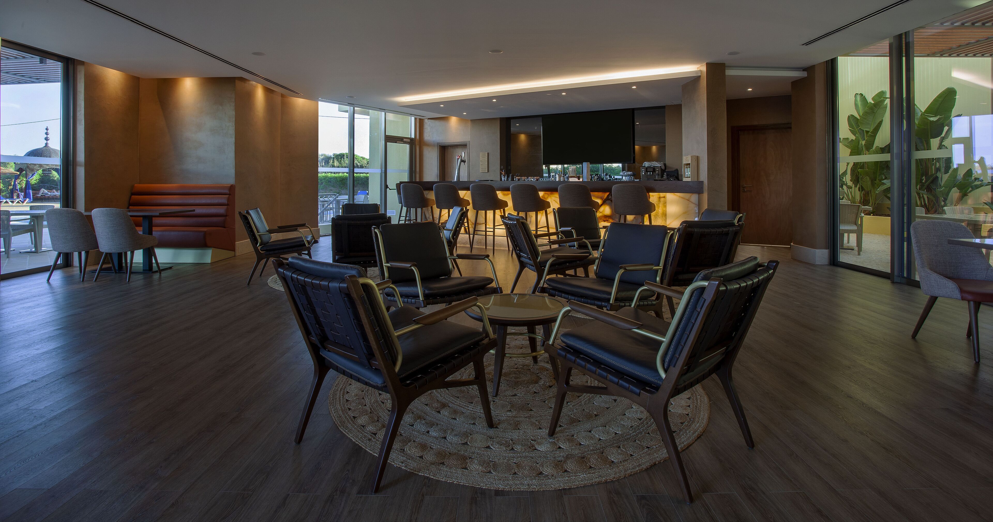 A modern lounge area with a bar, seating, and large windows.