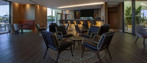 A modern lounge area with a bar, seating, and large windows.